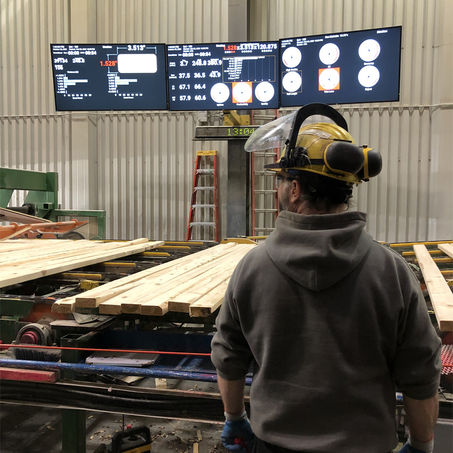 Operator looking at lumber rolling by with PMP WePlane dashboards in the background