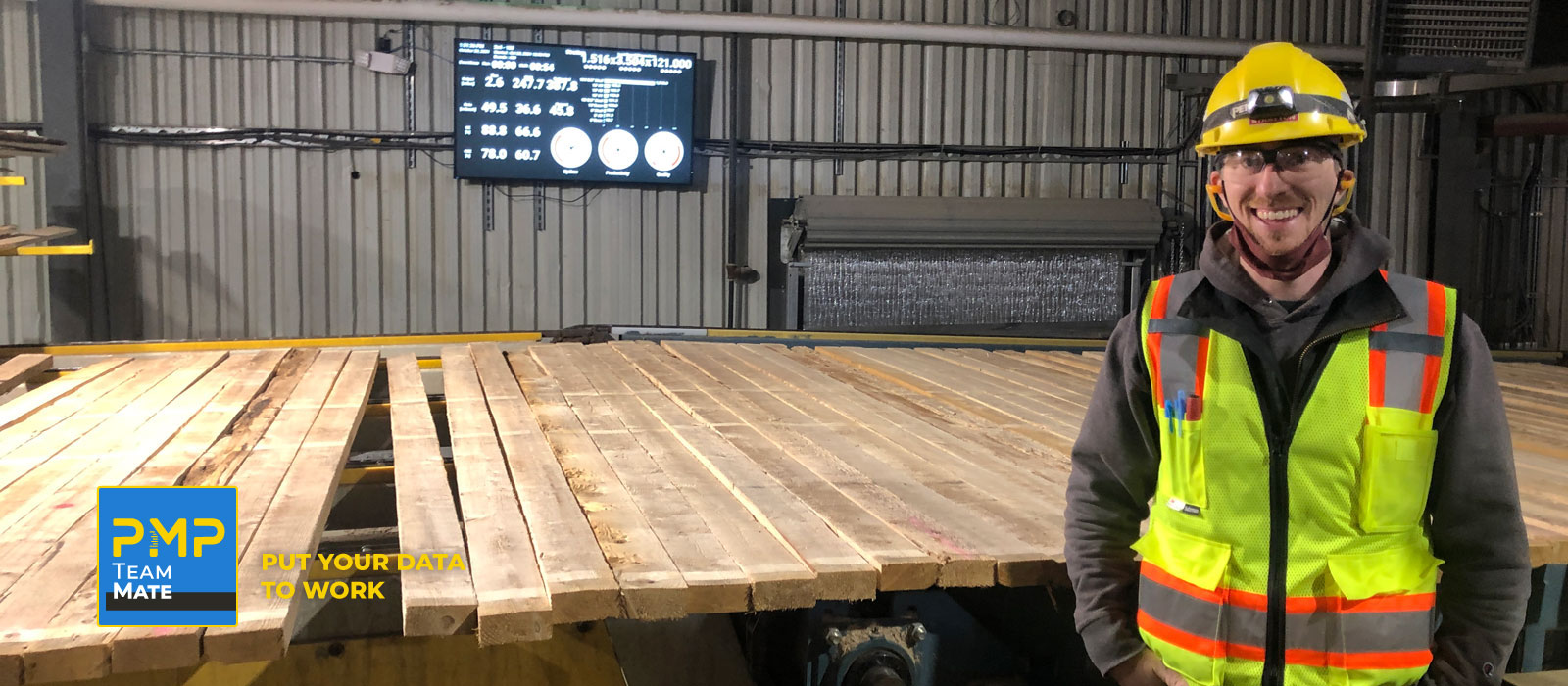Smiling plant manager in front of lumber line and PMP TeamMate dashboard